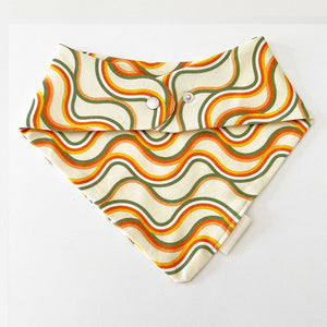 Bohemian Babies made in the USA organic cotton bandana bib. Snap closure. Catch The Wave print. Retro orange, green and mustard waves on an off-white background. Back view.