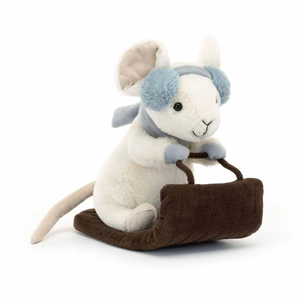 White plush mouse with blue earmuffs riding a brown velvet sleigh.